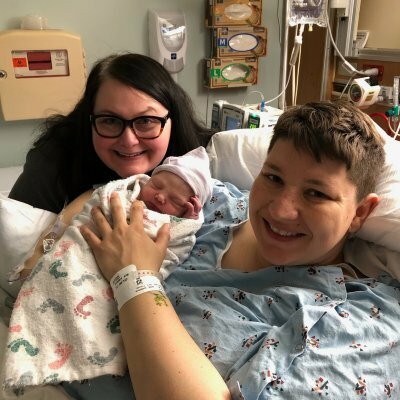 two women smiling holding baby